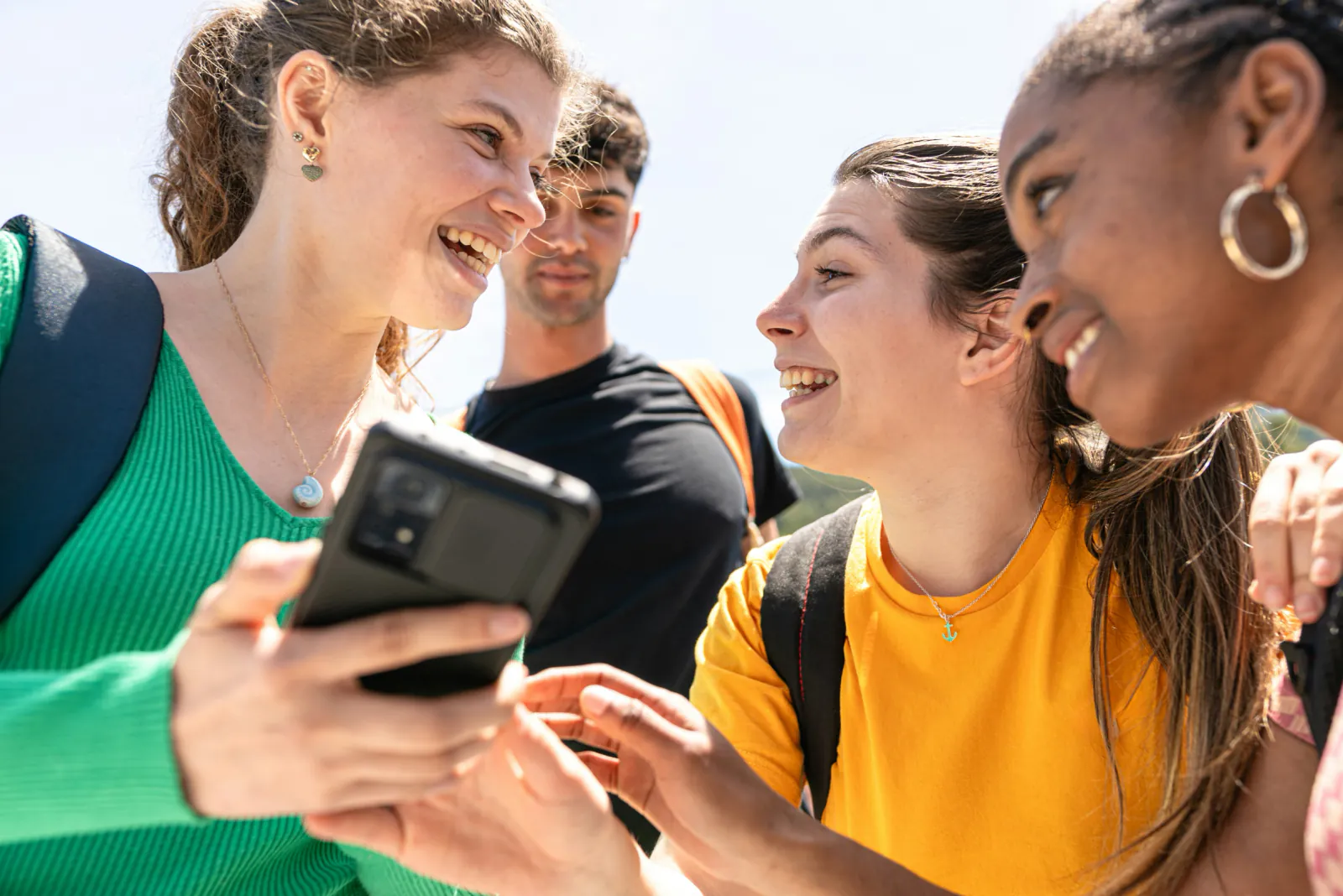 A group of young adults sharing something on a phone